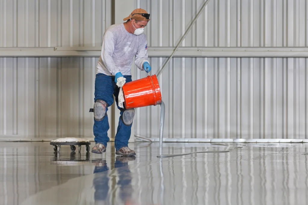 Worker applying traditional industrial floor coating with protective gear—demonstrating the odor and exposure risks BioBond helps eliminate